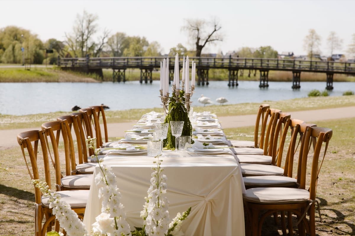 Lange trouwtafel met crossback stoelen aan het water